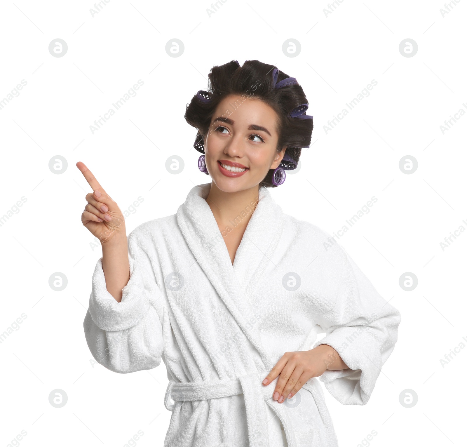 Photo of Happy young woman in bathrobe with hair curlers on white background