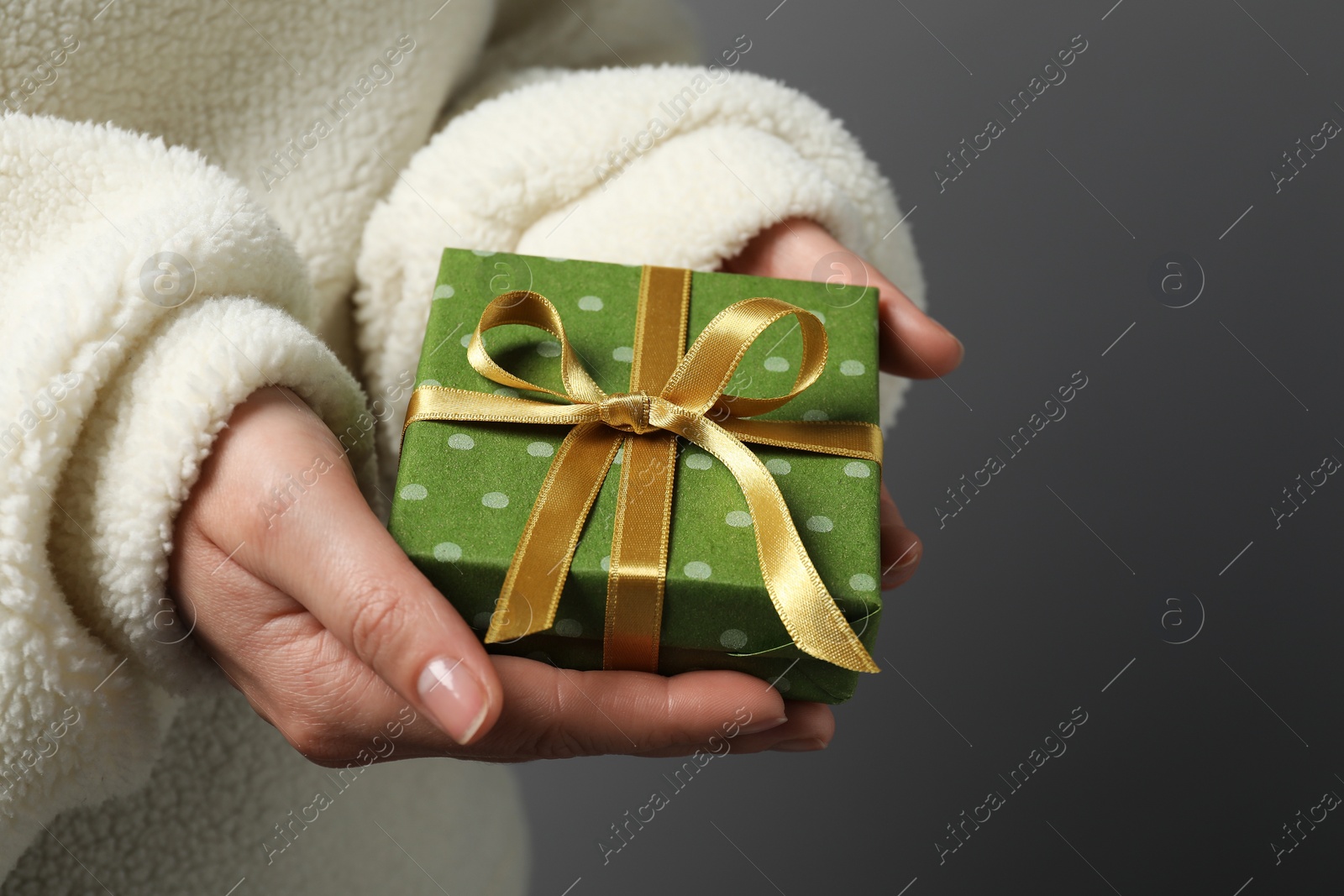 Photo of Christmas present. Woman holding gift box against grey background, closeup. Space for text