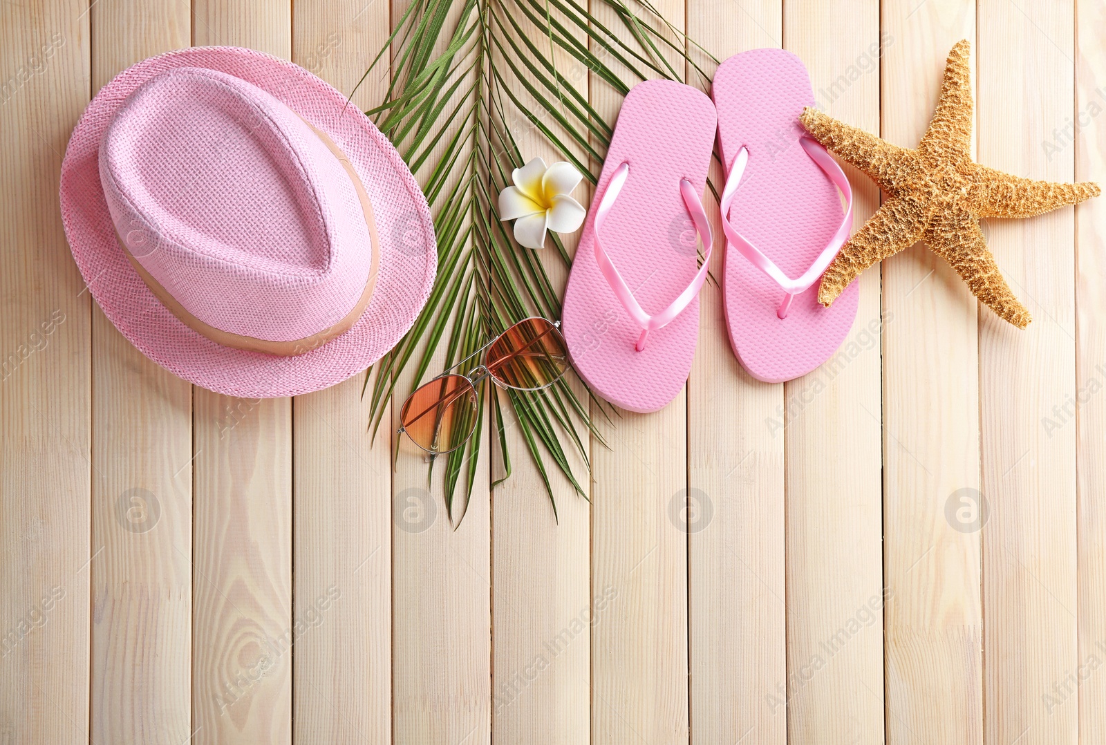 Photo of Flat lay composition with stylish hat and beach objects on wooden background