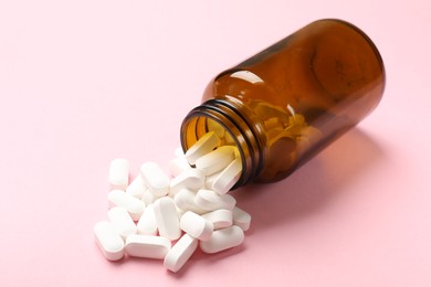 Photo of Bottle and vitamin capsules on pink background