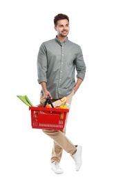 Young man with shopping basket full of products isolated on white