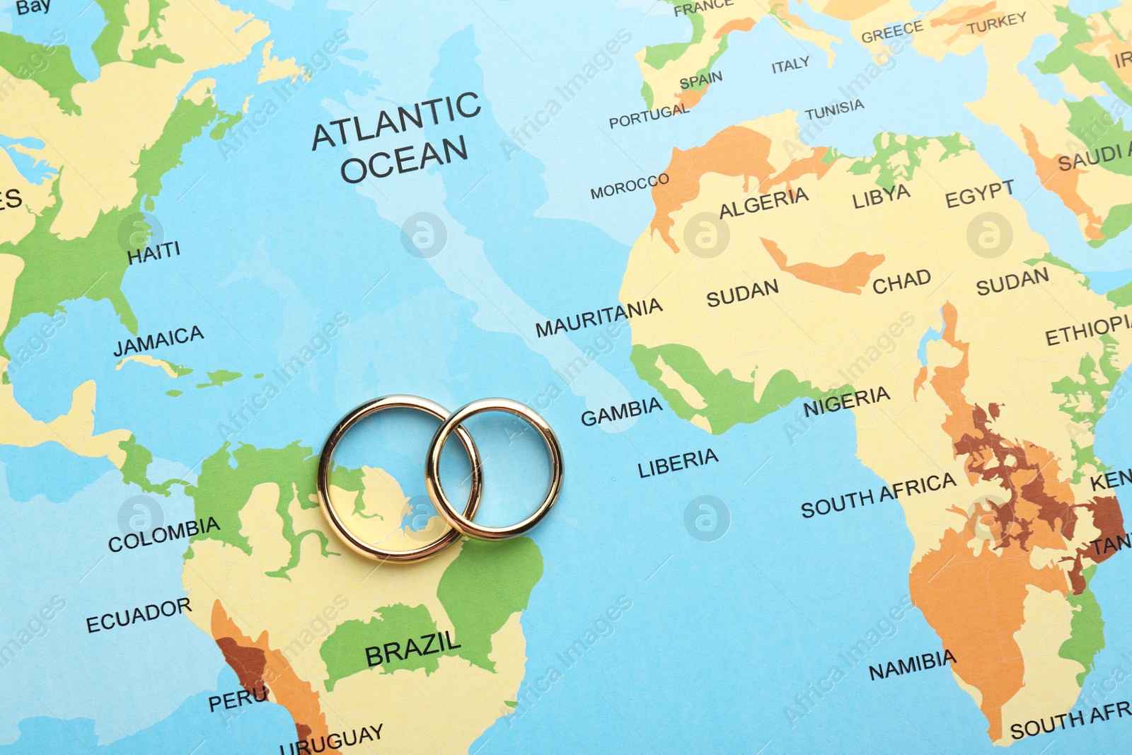 Photo of Honeymoon concept. Two golden rings on world map, top view