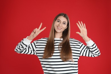 Photo of Woman showing number seven with her hands on red background