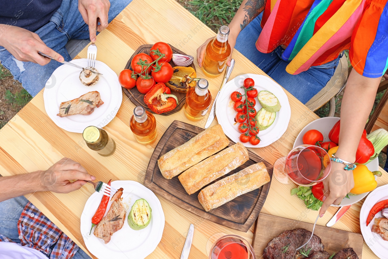 Photo of Young people having barbecue at table outdoors, top view