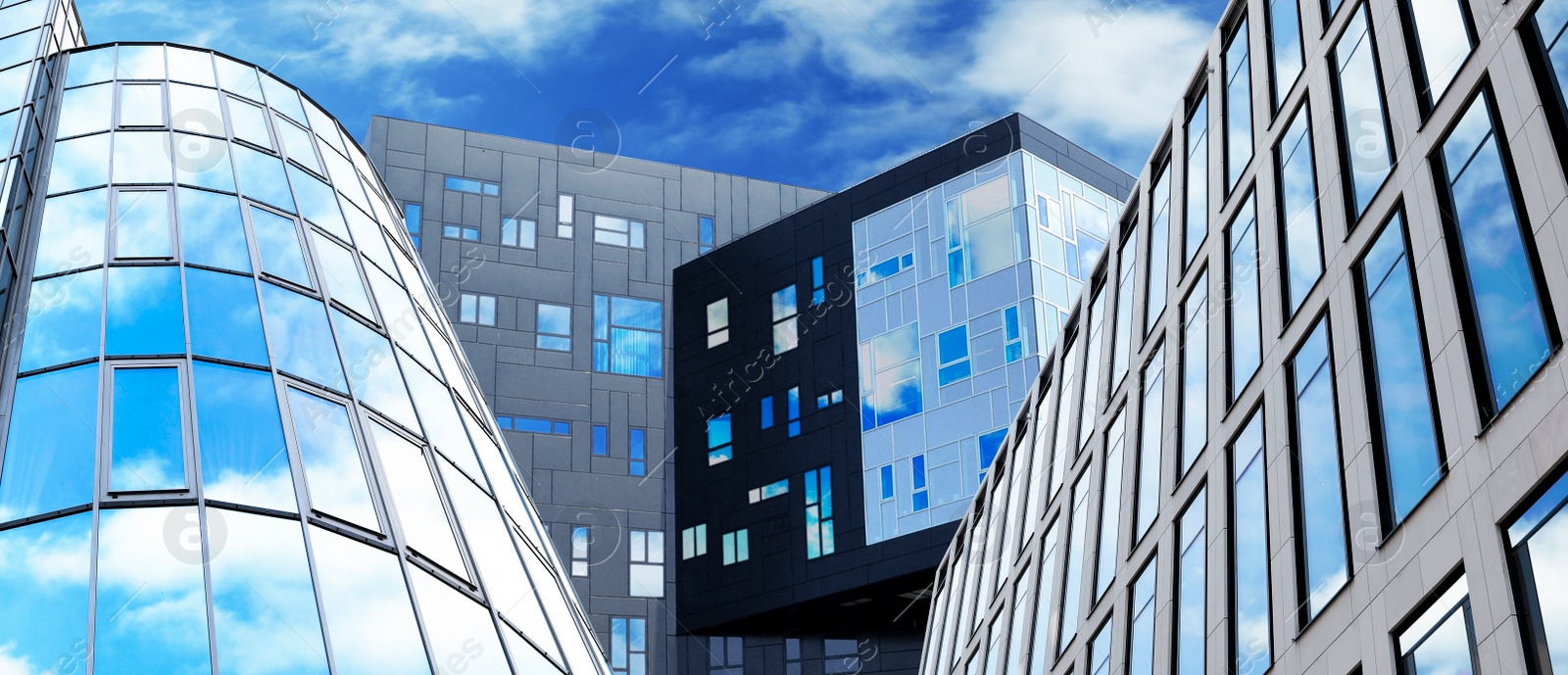 Image of Beautiful blue sky with clouds reflecting in windows of modern buildings, low angle view. Banner design