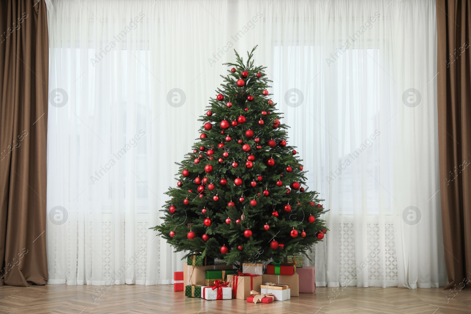 Photo of Beautifully decorated Christmas tree and gifts near window indoors