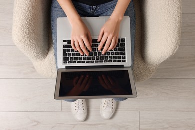 Photo of Woman working with laptop in armchair, top view