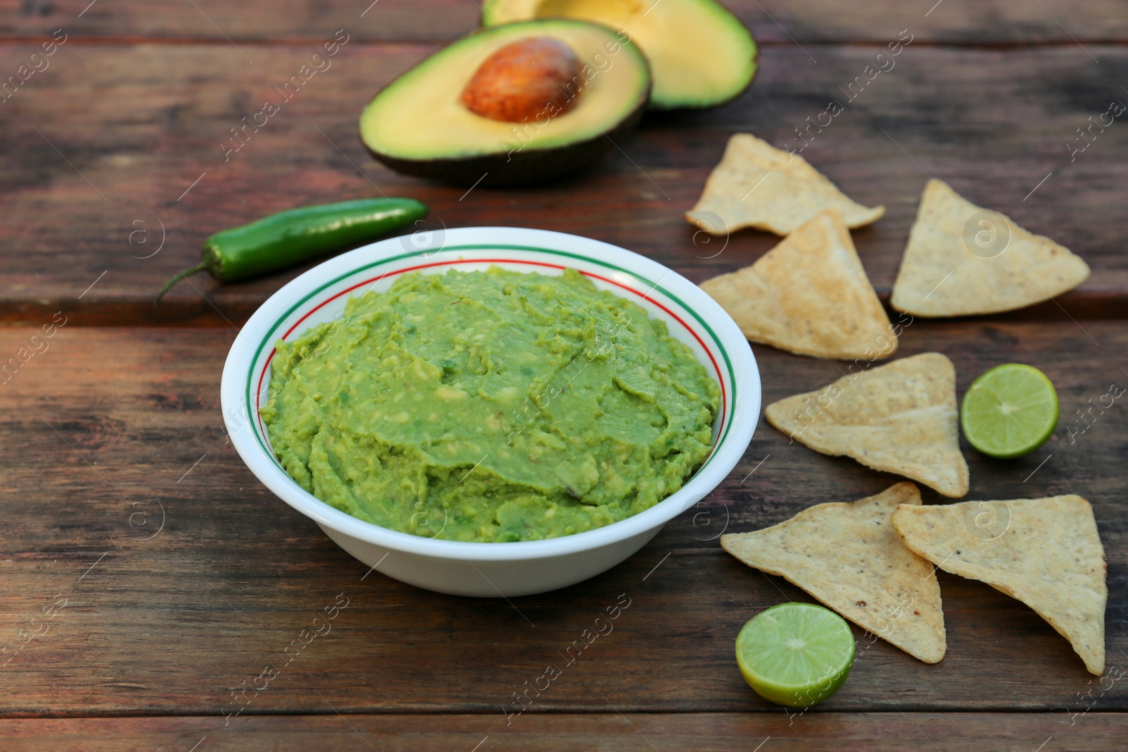 Photo of Delicious guacamole made of avocados with nachos on wooden table