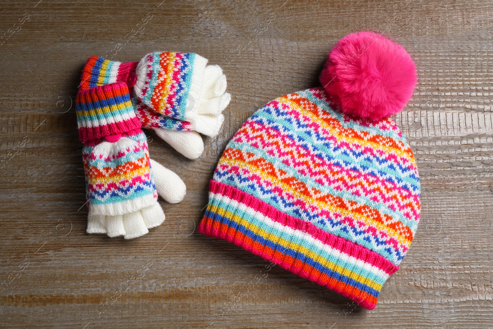 Photo of Warm knitted hat and mittens on wooden background, flat lay