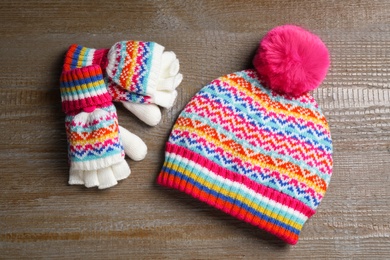 Warm knitted hat and mittens on wooden background, flat lay