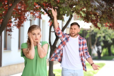 Photo of Young couple arguing on street. Problems in relationship