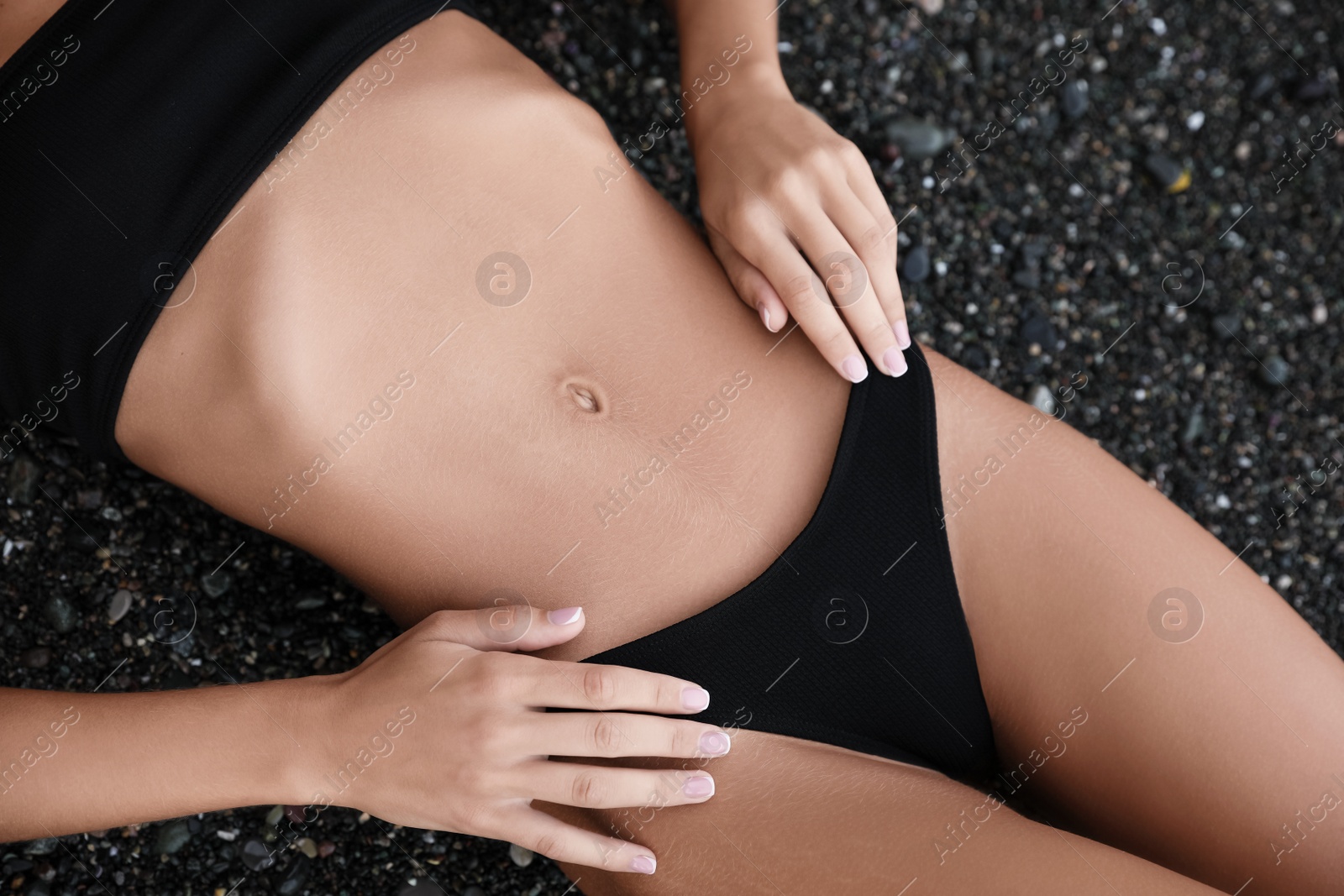 Photo of Sexy young woman in stylish bikini lying on seashore, closeup