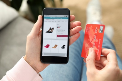 Photo of Woman with credit card using smartphone for online shopping indoors, closeup