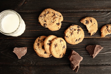 Photo of Flat lay composition with chocolate chip cookies and jar of milk on wooden background