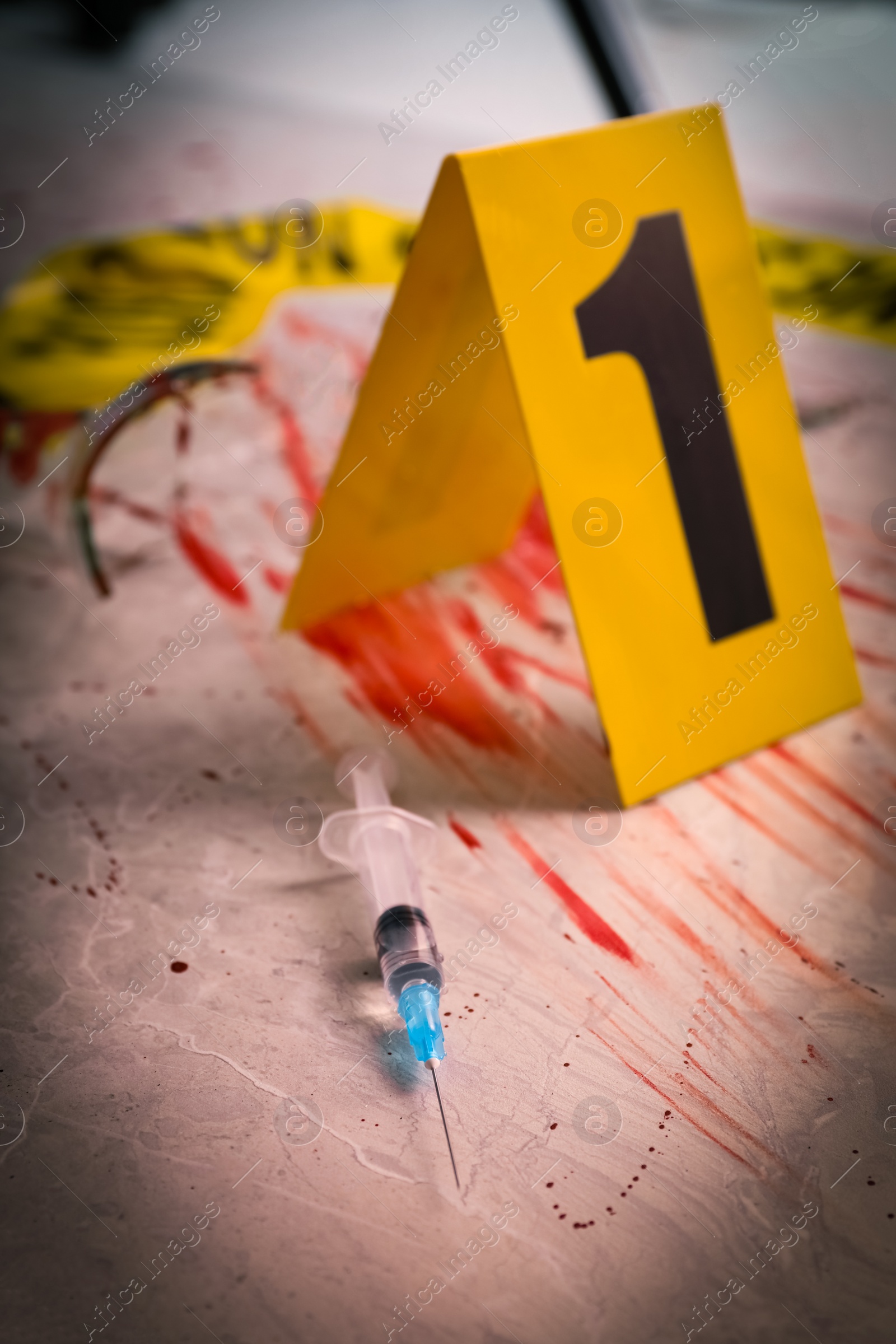 Photo of Syringe in blood and crime scene marker on marble table, closeup