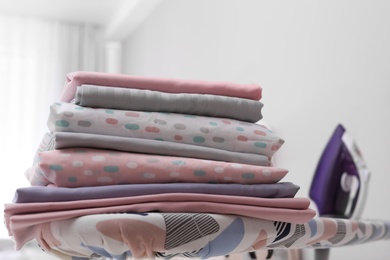Stack of clean bed linens on ironing board in room