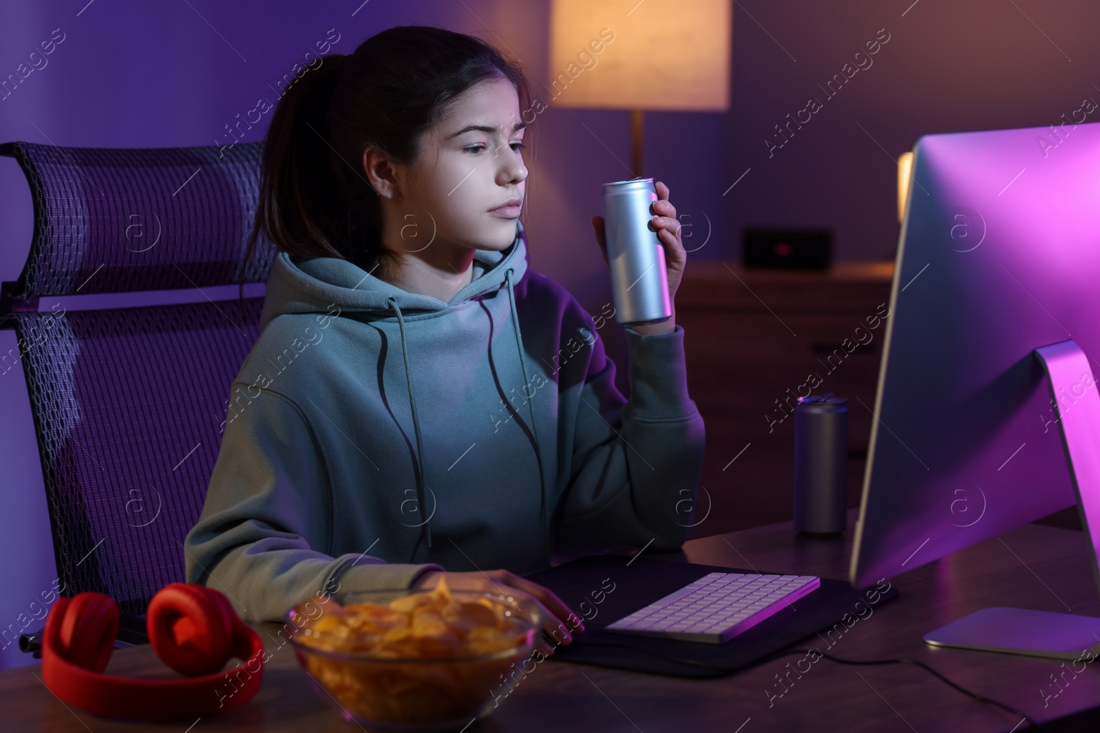 Photo of Girl with energy drink playing computer game at table in room