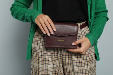 Young African American woman with stylish waist bag on grey background, closeup