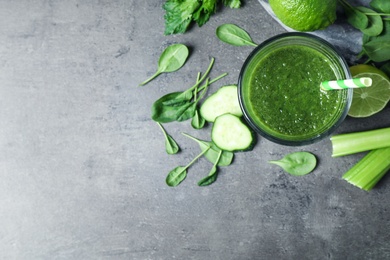 Green juice and fresh ingredients on grey table, flat lay. Space for text