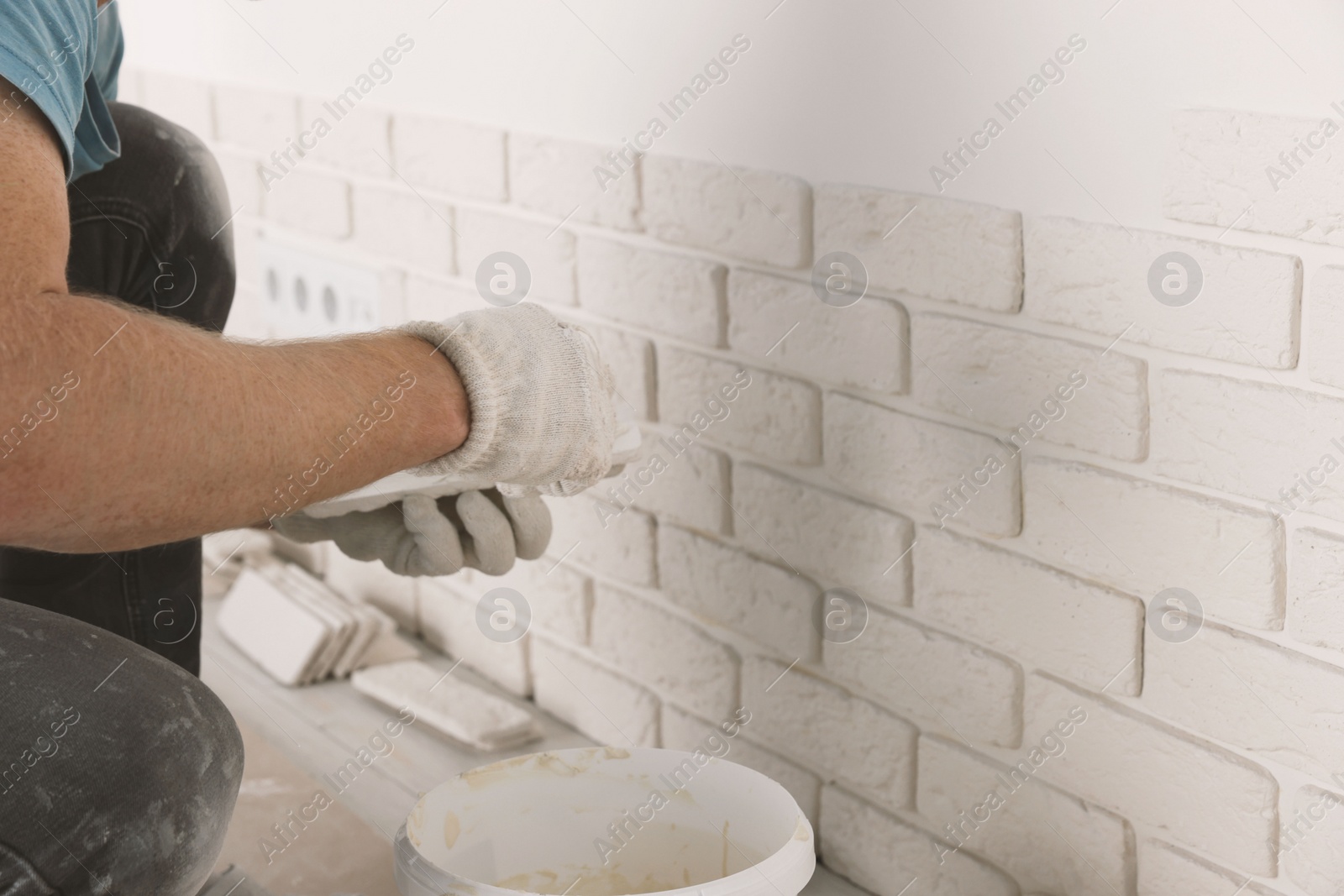 Photo of Worker installing decorative wall tiles in room, closeup