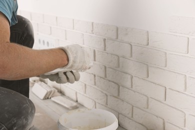 Photo of Worker installing decorative wall tiles in room, closeup