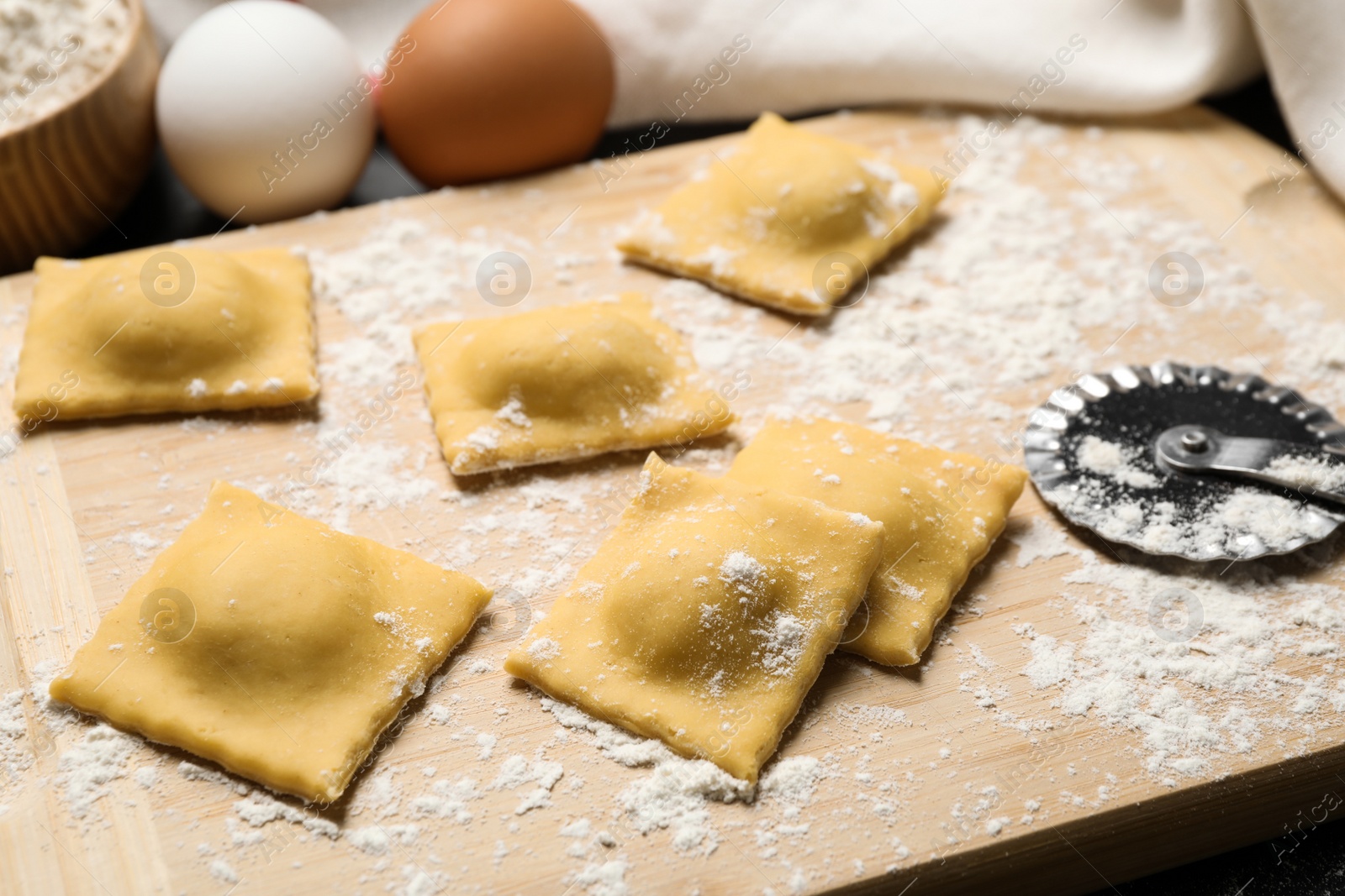 Photo of Raw ravioli on wooden board, closeup view. Italian pasta