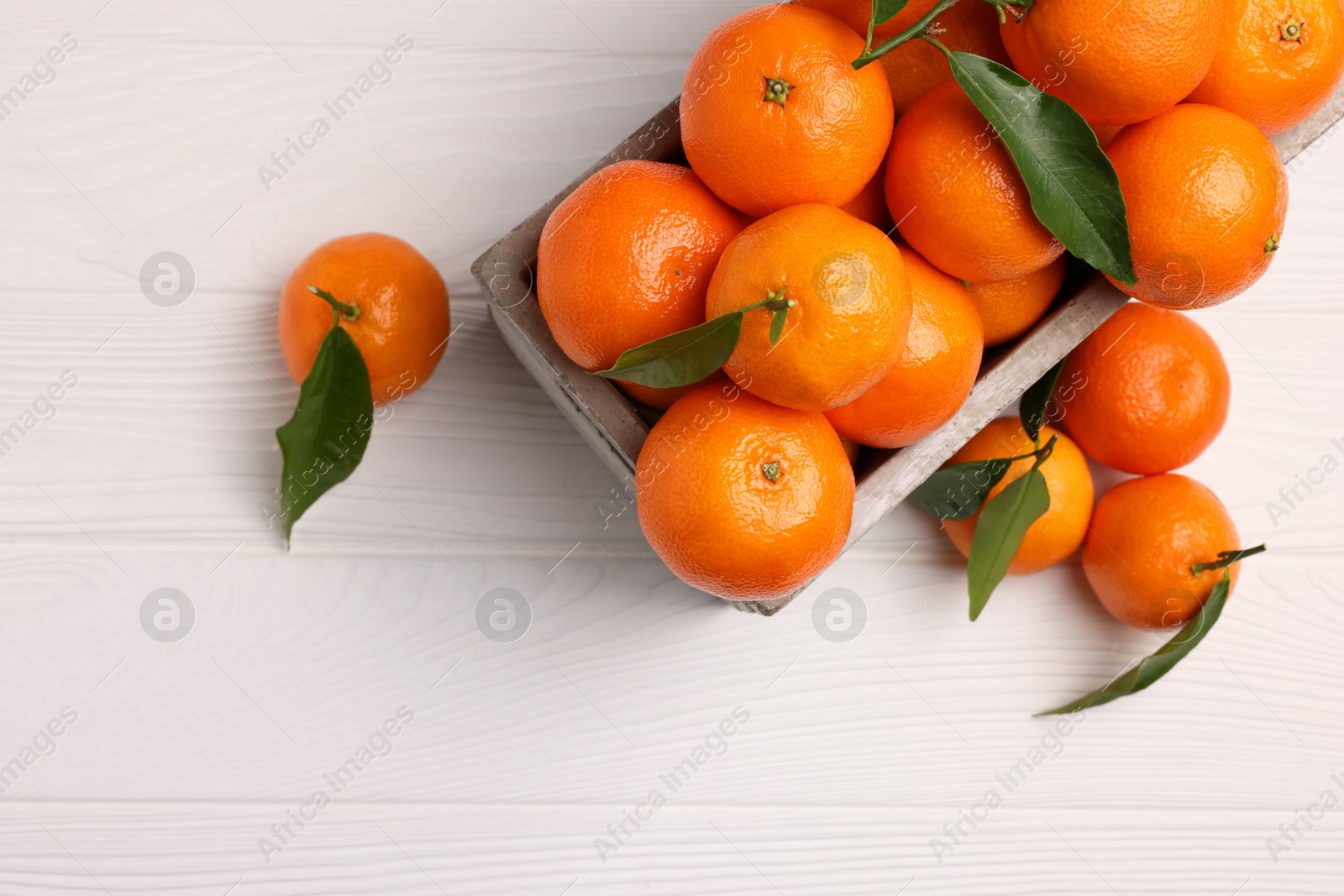 Photo of Delicious tangerines with leaves on white wooden table, top view. Space for text