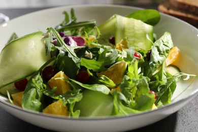 Delicious salad with cucumber and orange slices in bowl on table, closeup