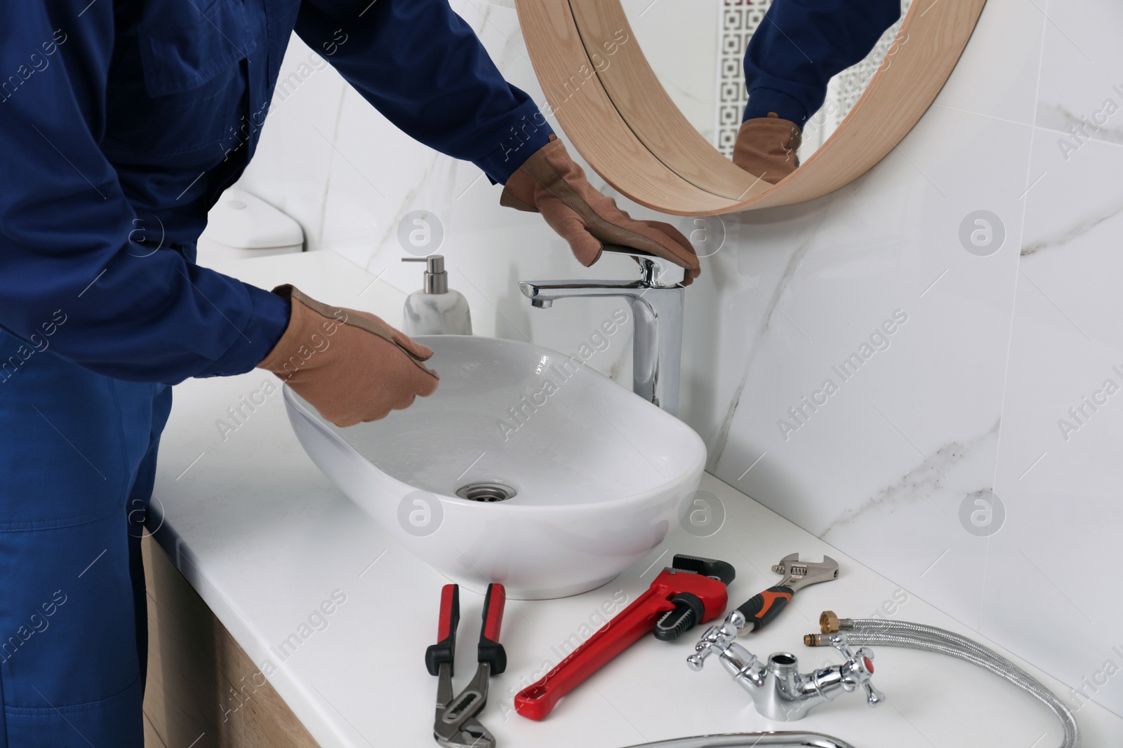 Photo of Professional plumber checking water tap in bathroom, closeup
