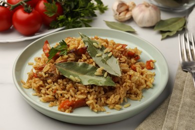 Photo of Delicious pilaf, bay leaves and ingredients on white table