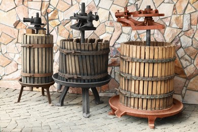 Photo of Metal winepresses in wooden barrels near stone wall outdoors