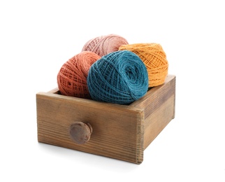 Wooden drawer with clews of colorful knitting threads on white background