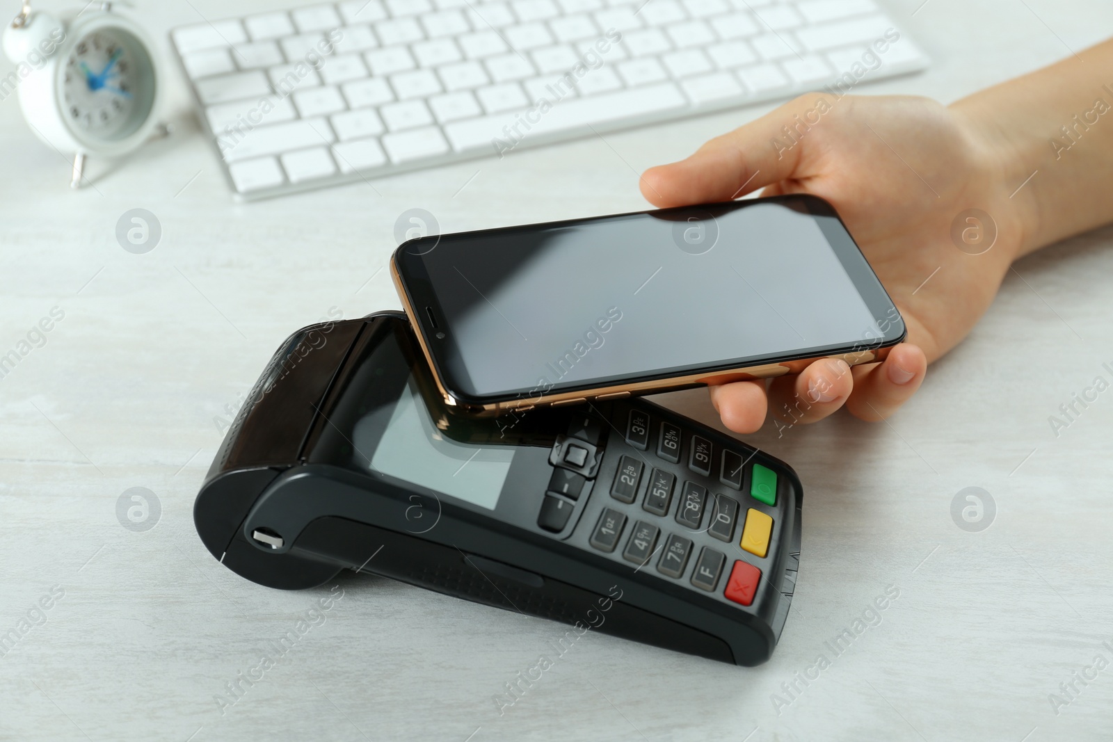 Photo of Woman with credit card using modern payment terminal at white table, closeup