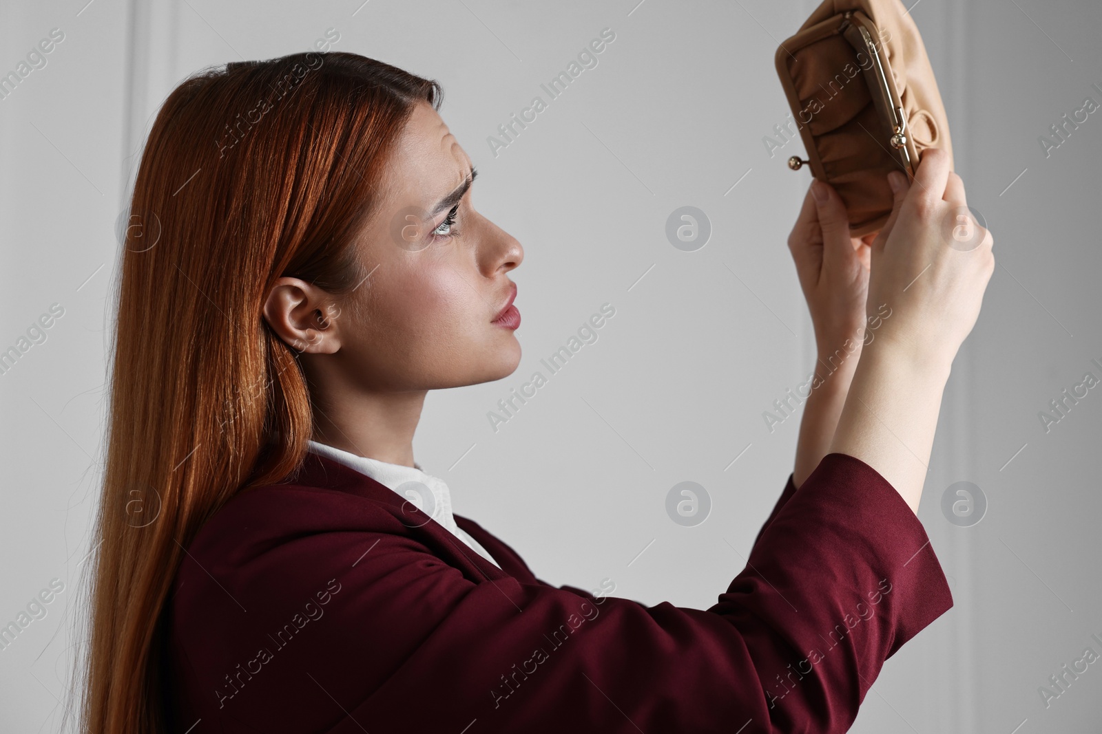 Photo of Upset woman with empty wallet near white wall