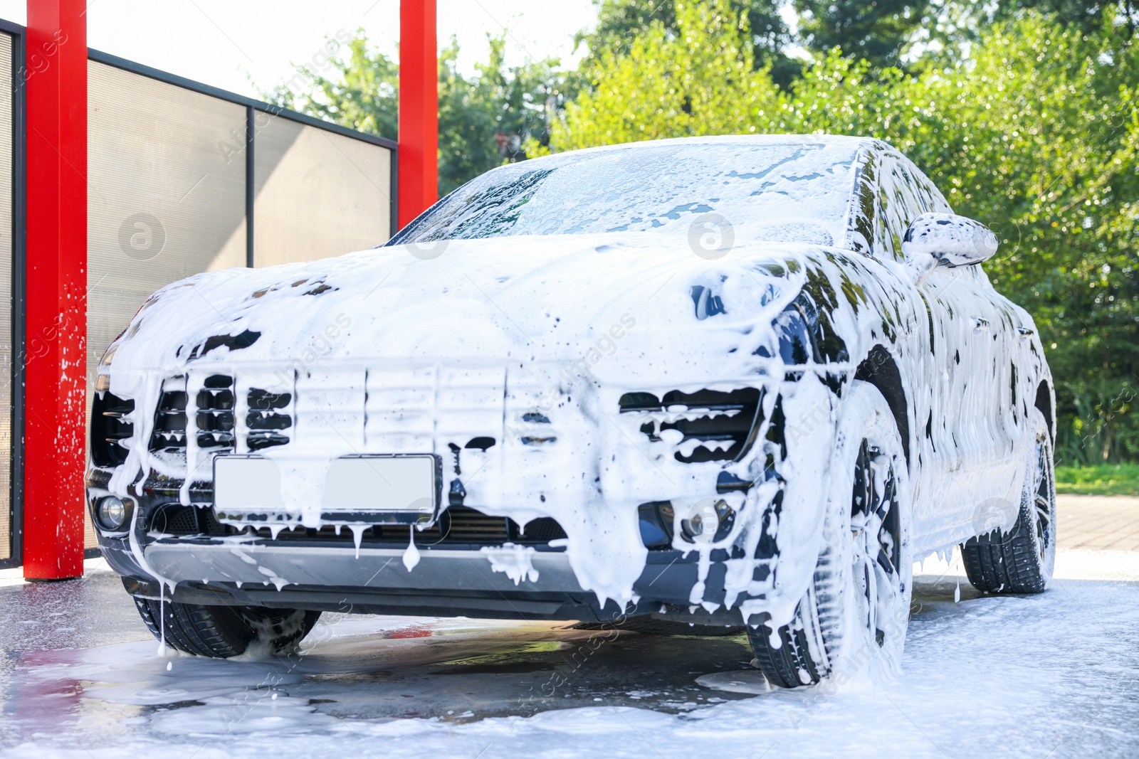 Photo of Auto covered with cleaning foam at outdoor car wash