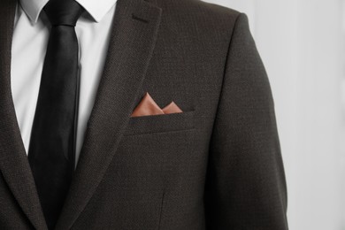 Photo of Man with handkerchief in breast pocket of his suit on light background, closeup