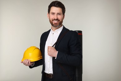 Architect with drawing tube and hard hat on gray background