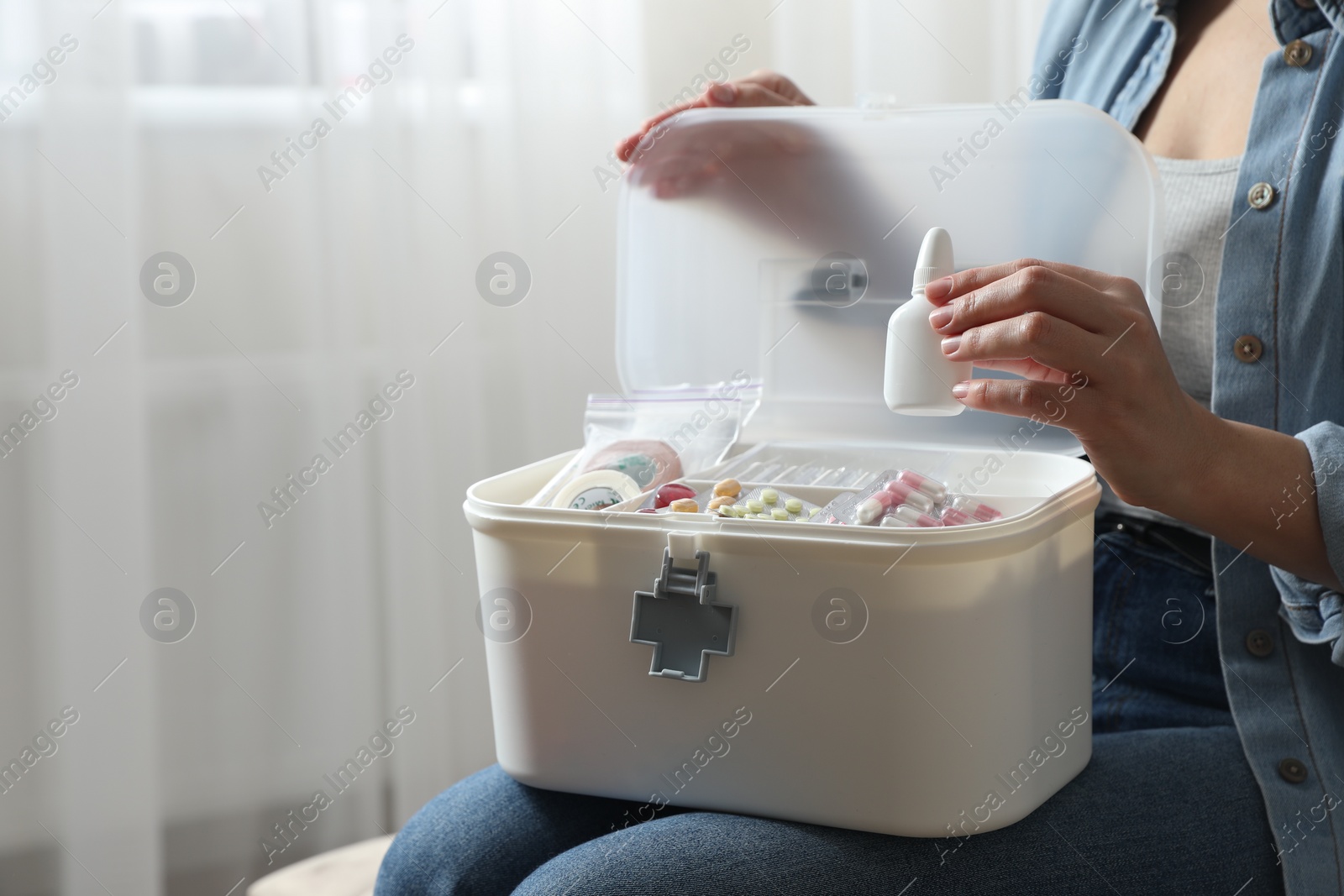 Photo of Woman putting medicament into first aid kit indoors, closeup. Space for text