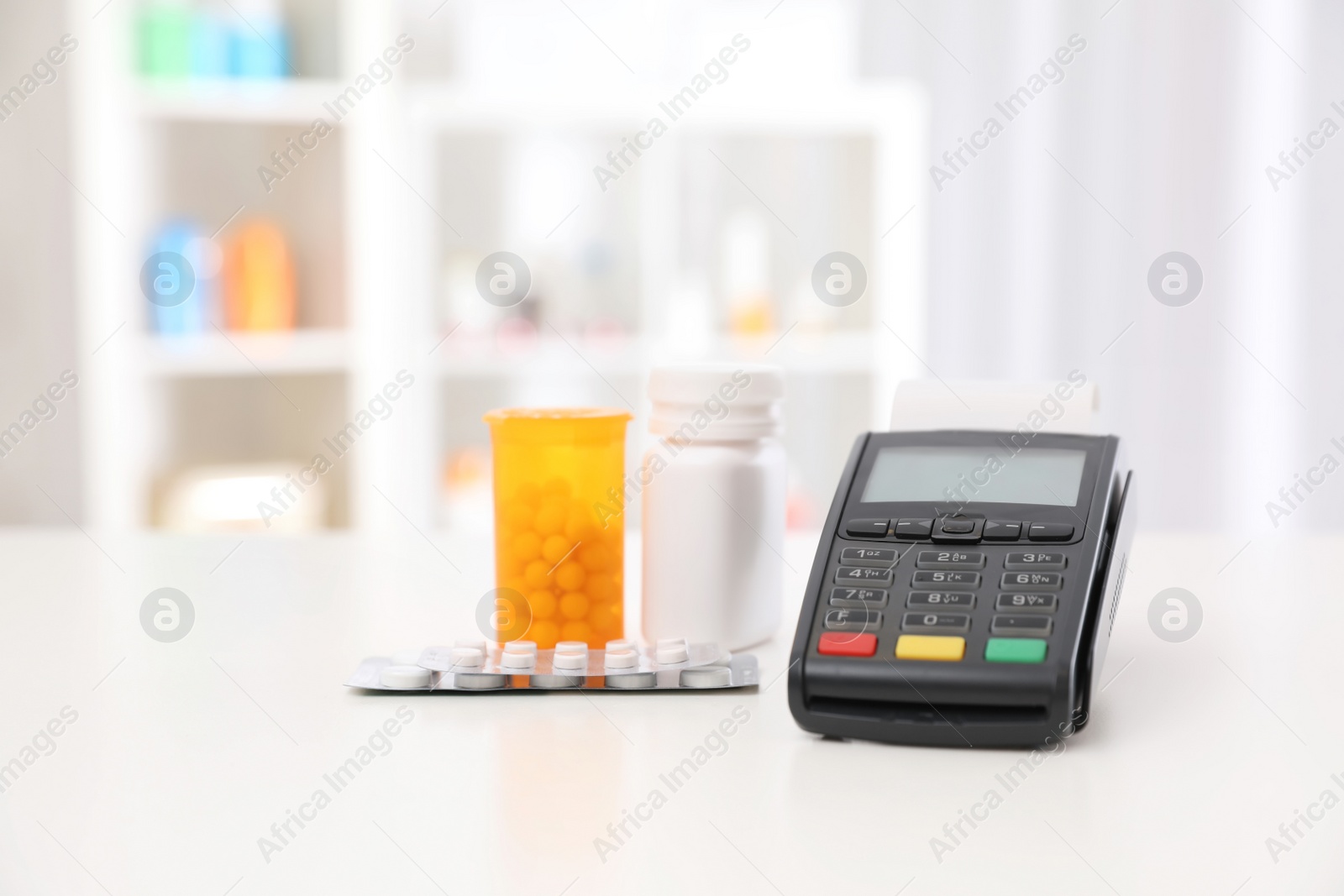 Photo of Payment terminal and pills on counter in pharmacy. Space for text