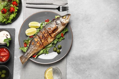 Photo of Flat lay composition with delicious sea bass fish, sauces and ingredients served on light grey table. Space for text