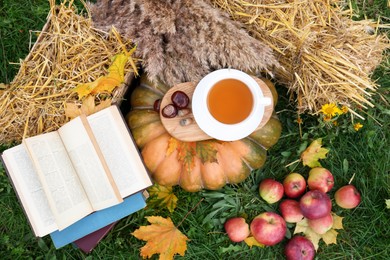 Photo of Books, pumpkin, apples and cup of tea outdoors, flat lay. Autumn season