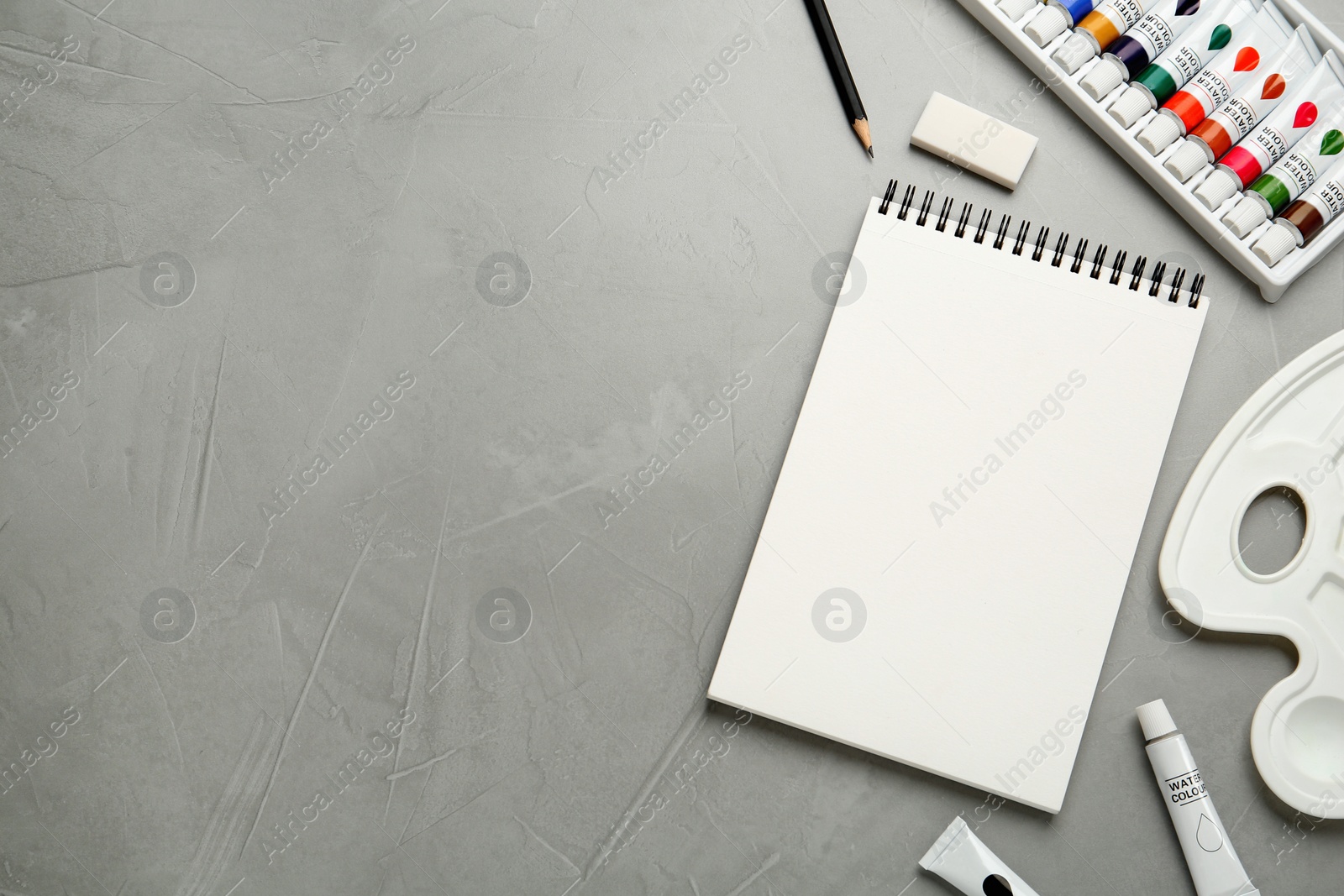 Photo of Flat lay composition with blank sketchbook on light grey stone table. Space for text