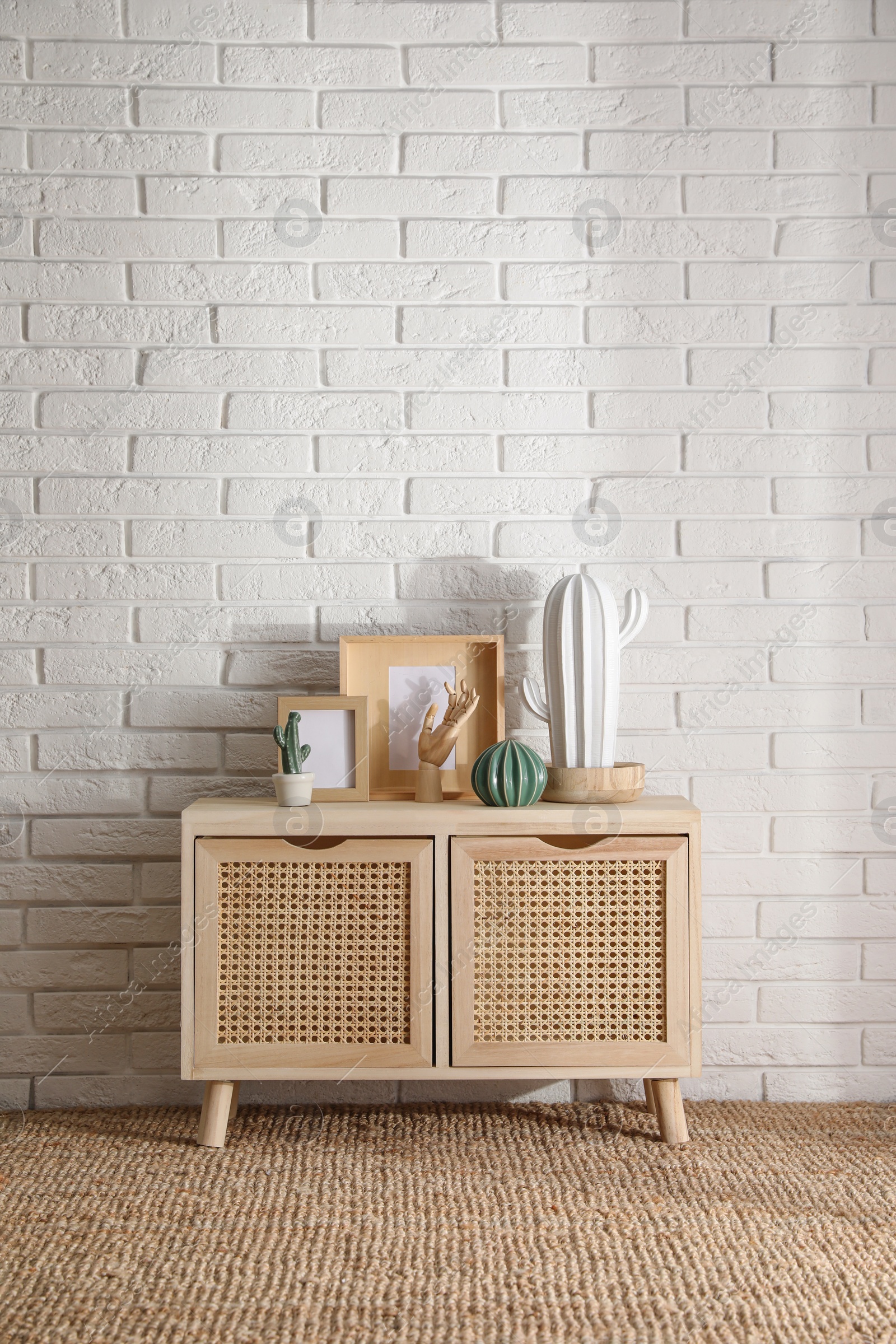 Photo of Stylish room interior with wooden cabinet near white brick wall