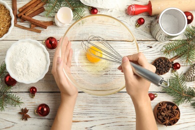 Photo of Woman cooking traditional Christmas cake at white wooden table with ingredients, top view