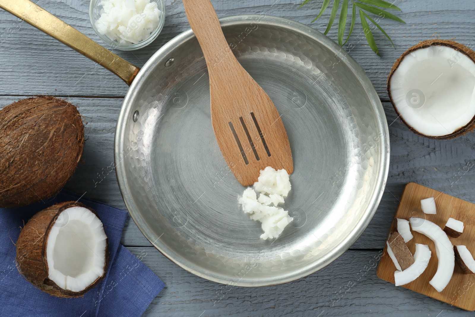 Photo of Flat lay composition with frying pan and organic coconut cooking oil on grey wooden table