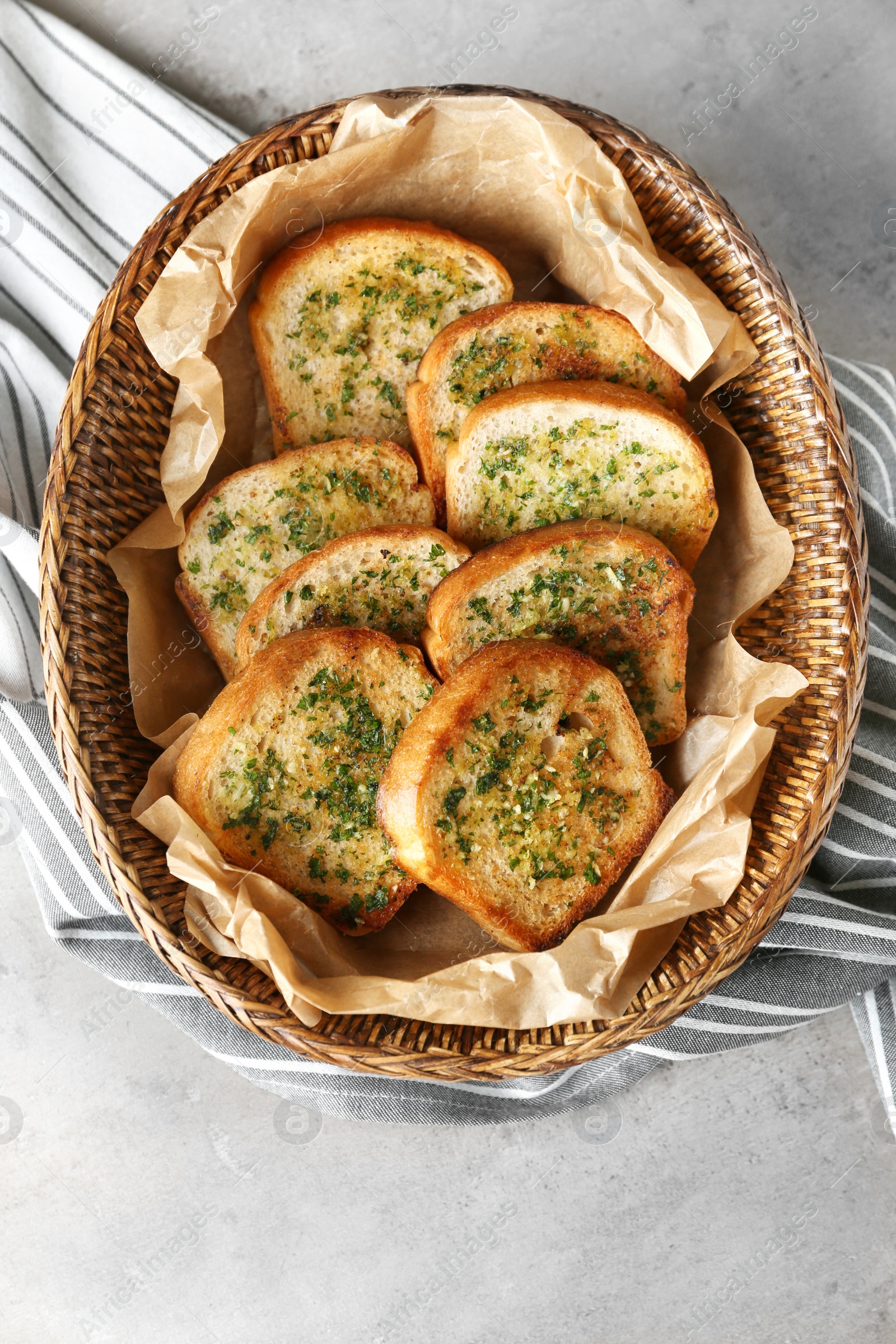 Photo of Slices of toasted bread with garlic and herbs on grey table, top view