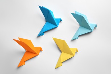 Photo of Beautiful colorful origami birds on white background, flat lay