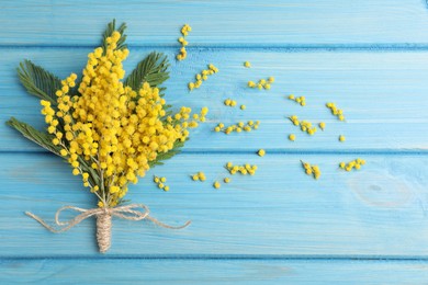 Beautiful mimosa flowers on light blue wooden table, flat lay. Space for text