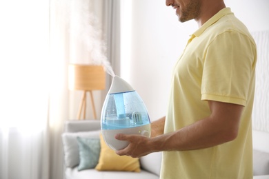 Man with modern air humidifier at home, closeup