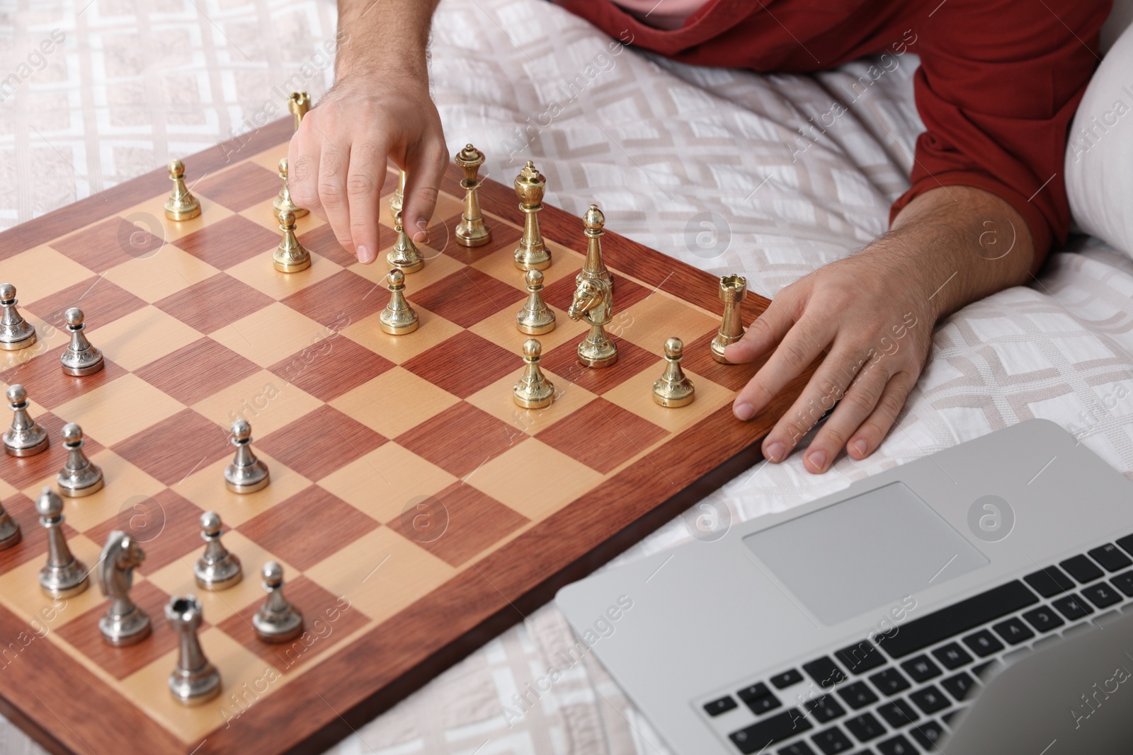 Photo of Man playing chess with partner through online video chat on bed, closeup